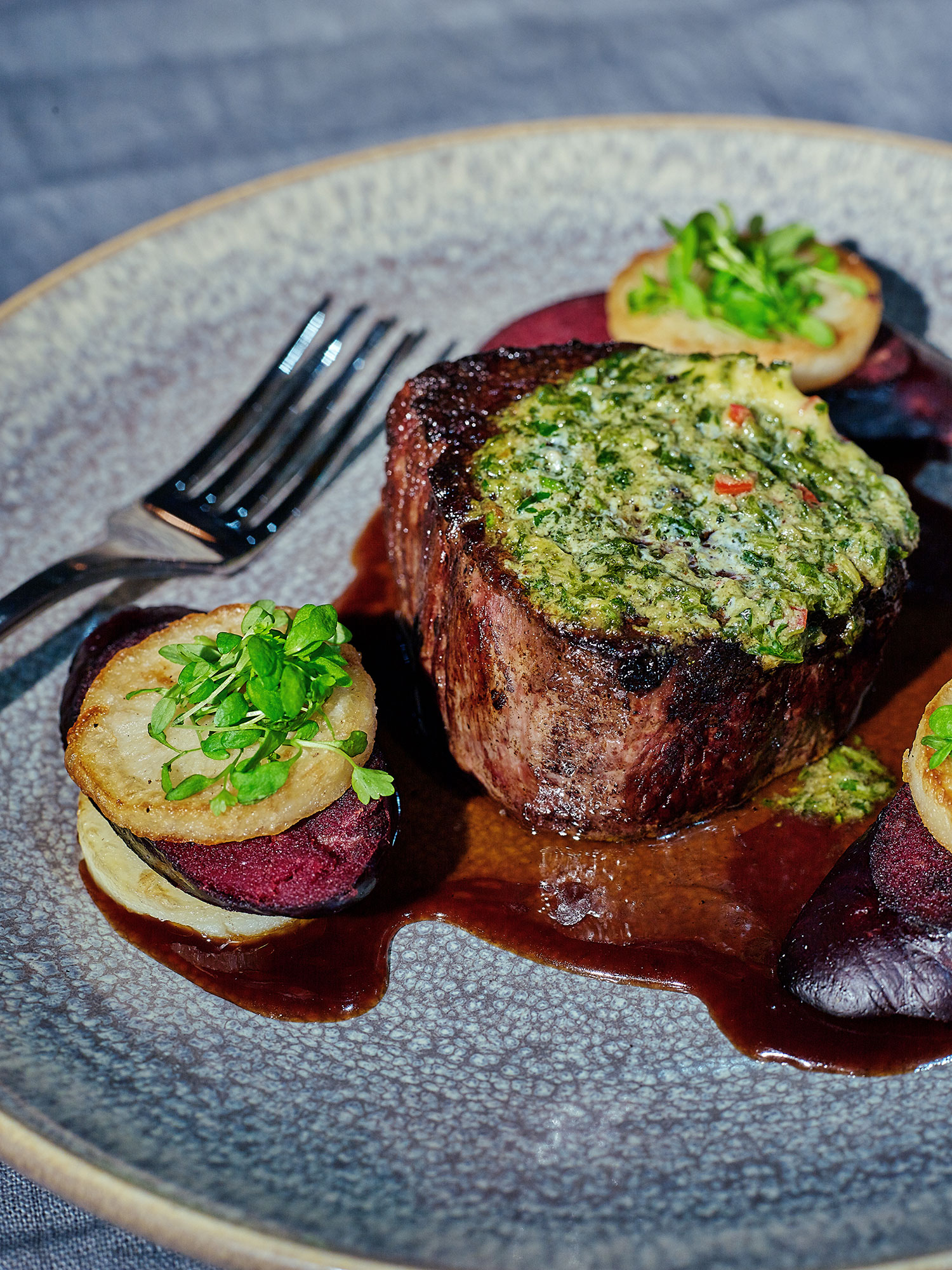 Angus eye fillet with fondant potato, black pudding and chimichurri butter and jus